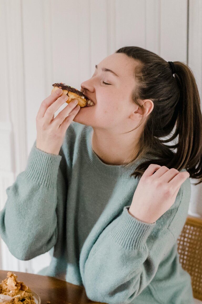 Person holding a donut near their mouth, considering a snack or craving
