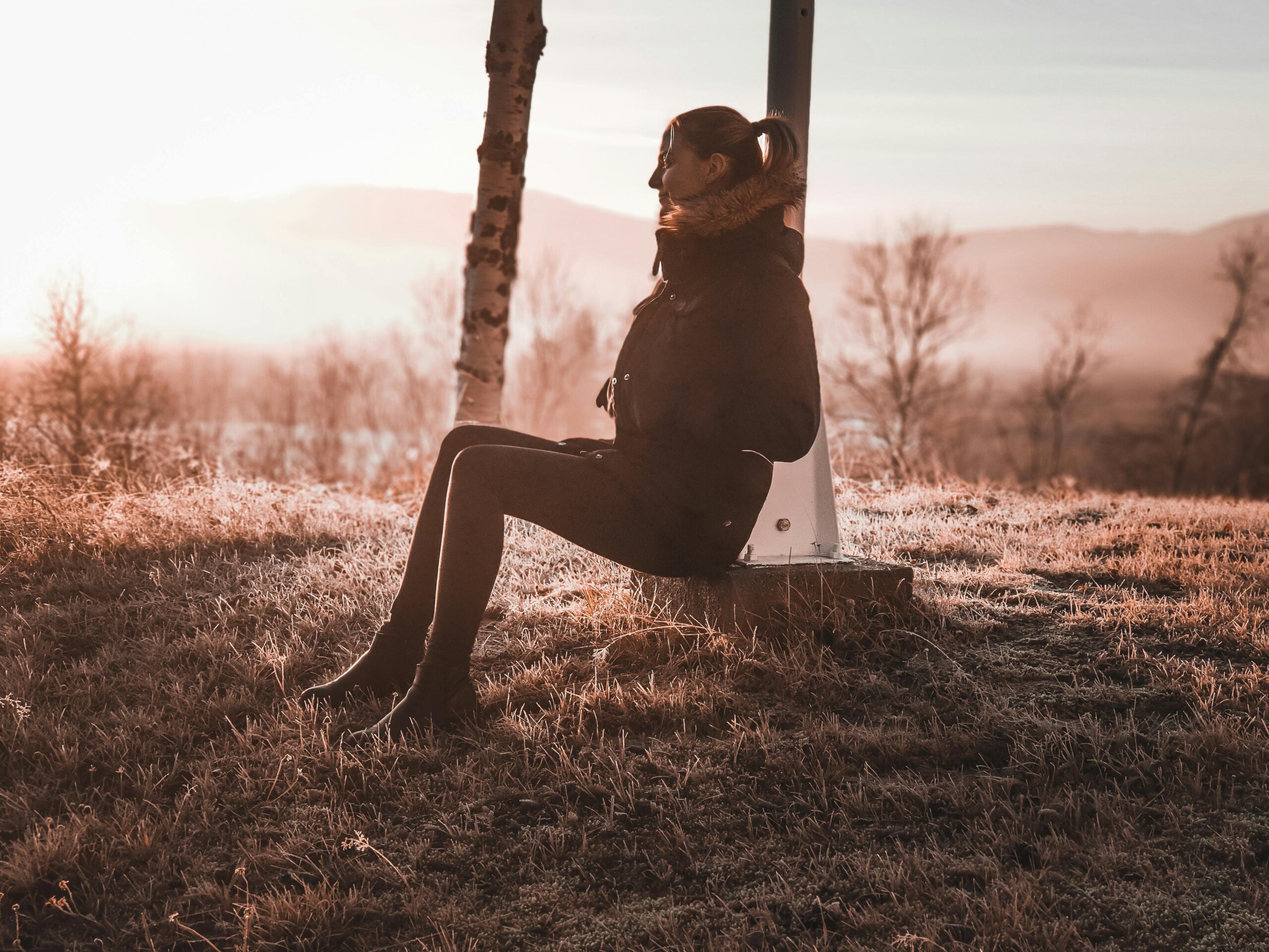 Woman sitting alone on a swing at sunset enjoying peace and solitude