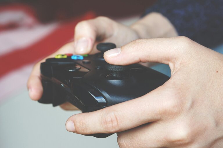 A hand tightly holding a game controller, symbolizing gaming addiction, control, and the struggle to disconnect