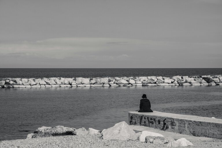 A person sitting alone in nature, surrounded by calm scenery and gentle light. for fear of death