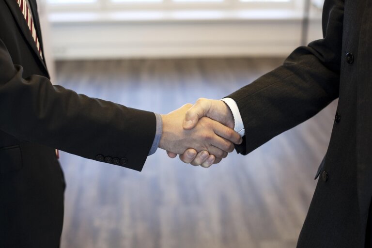 Two people shaking hands in a bright setting, symbolizing trust and connection. social anxiety
