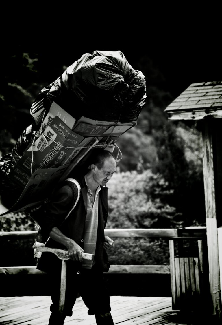 Person carrying a heavy load on their back, symbolizing perfectionism and unrealistic expectations affecting confidence, low self-esteem
