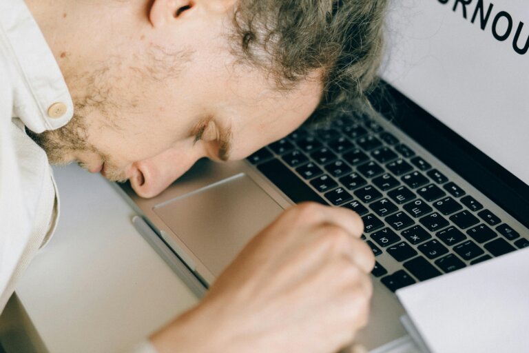 Tired and exhausted person lying on a desk, showing chronic fatigue and burnout